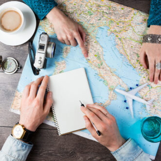 Two young people together planning trip to Europe. Top view. empty white space in notebook where you can place your text or advertisement. Romantic travel