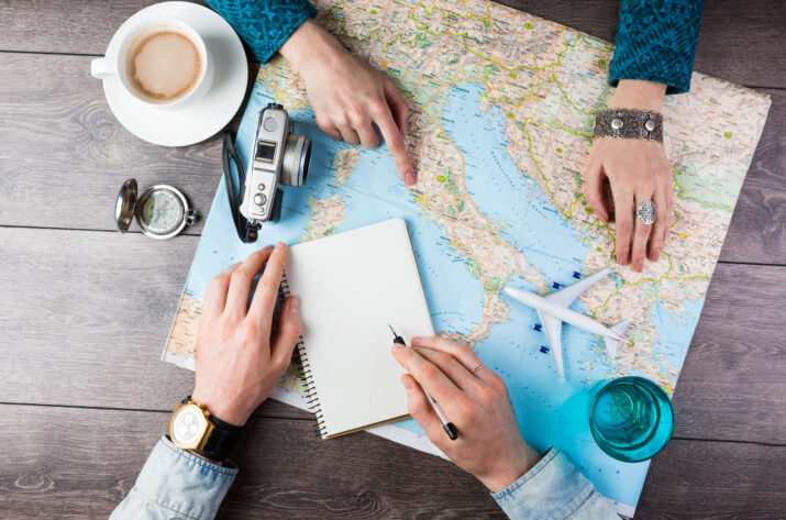 Two young people together planning trip to Europe. Top view. empty white space in notebook where you can place your text or advertisement. Romantic travel